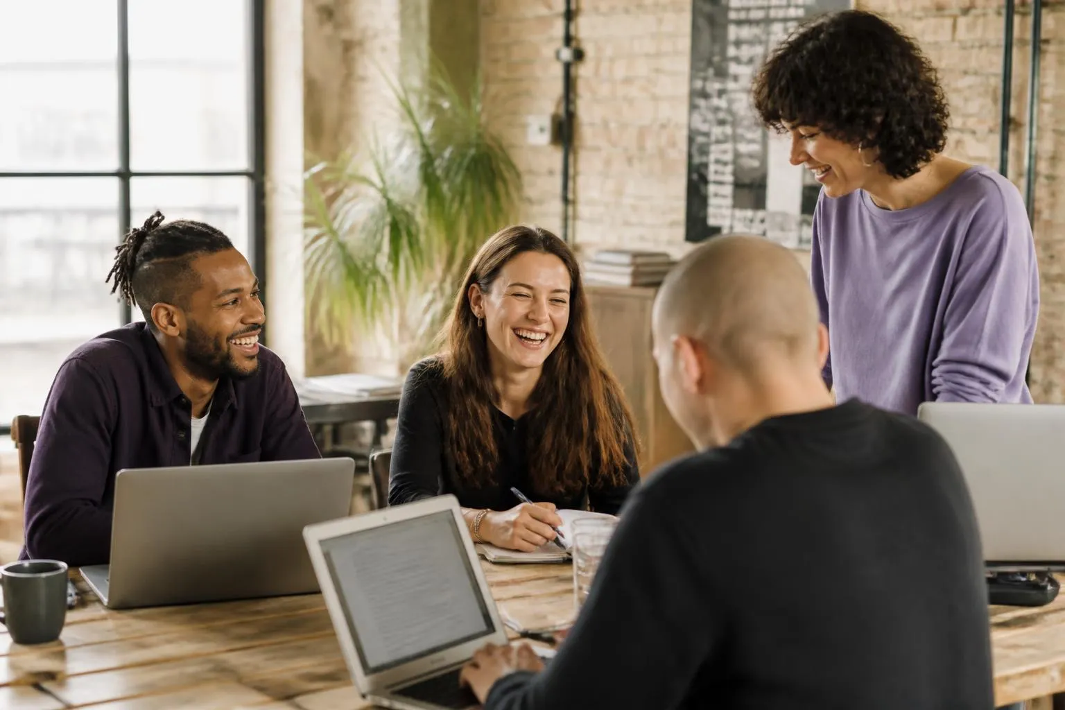 Team arbeitet gemeinsam an einem Tisch in einem hellen Loft-Büro