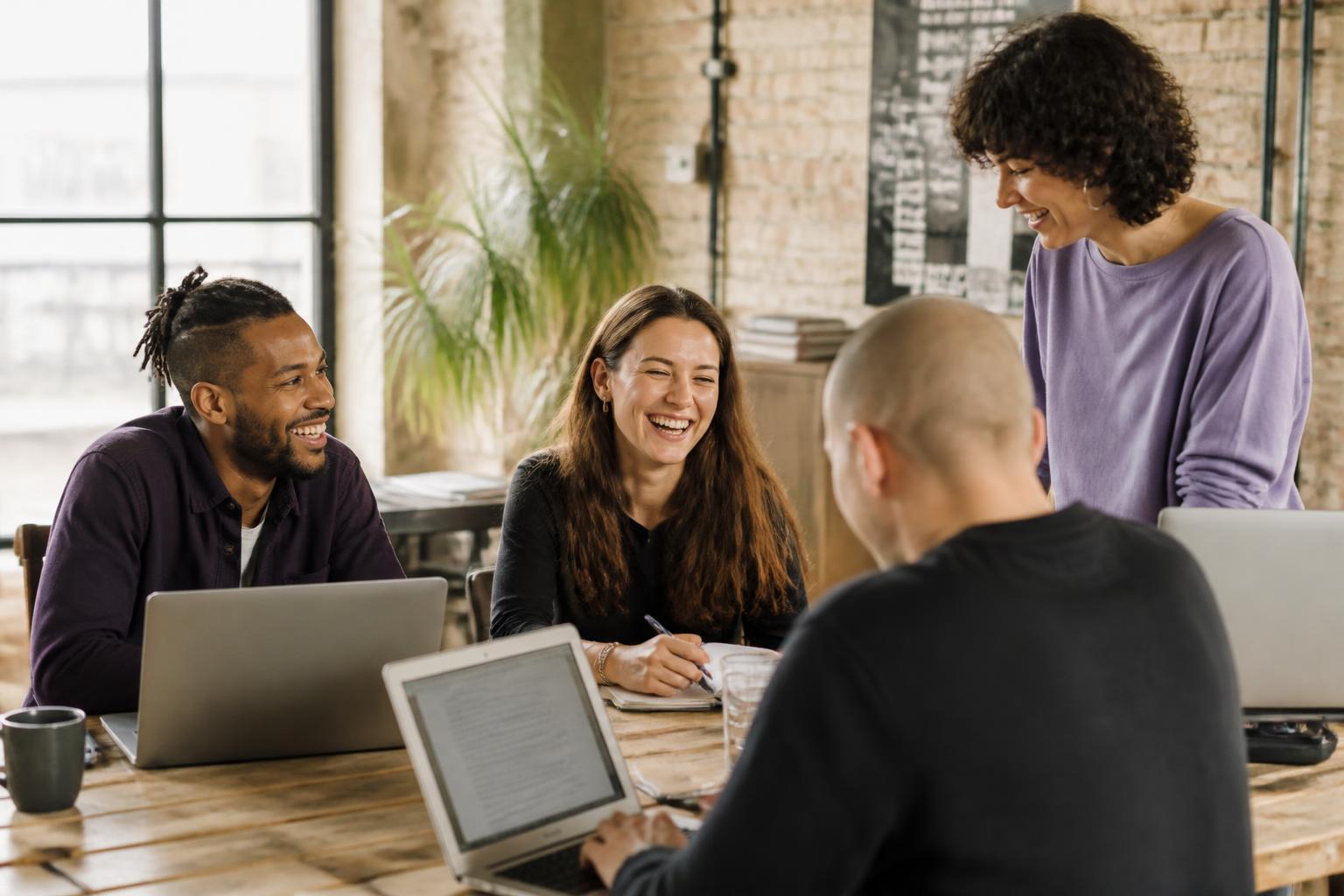 Team arbeitet gemeinsam an einem Tisch in einem hellen Loft-Büro